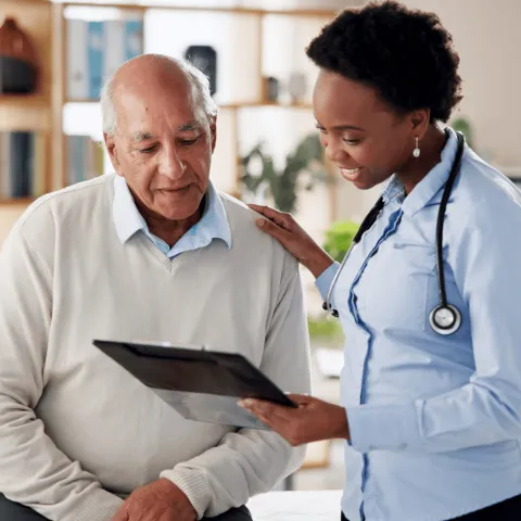A healthcare professional shows an elderly man information on a tablet in an office setting.