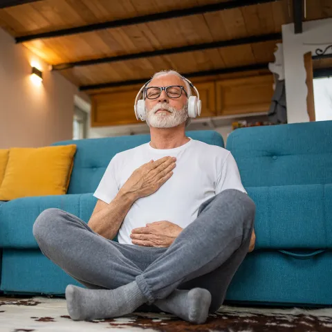 An older man meditating at home.