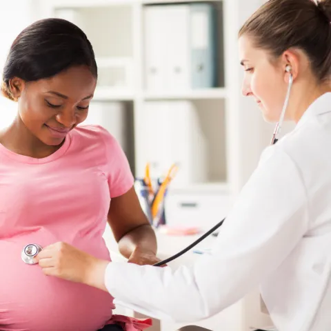 Doctor listening to pregnant woman's child in womb.