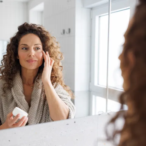 Female putting skin care on her face.