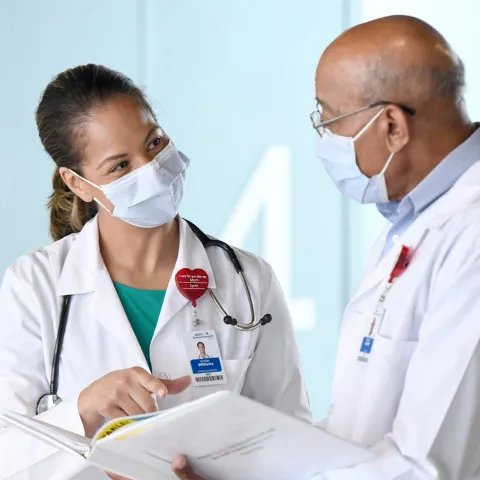 Two doctors talking while wearing masks.