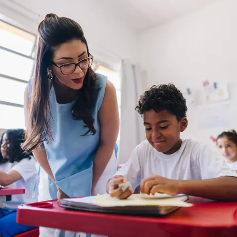Teacher Helping Student in Classroom
