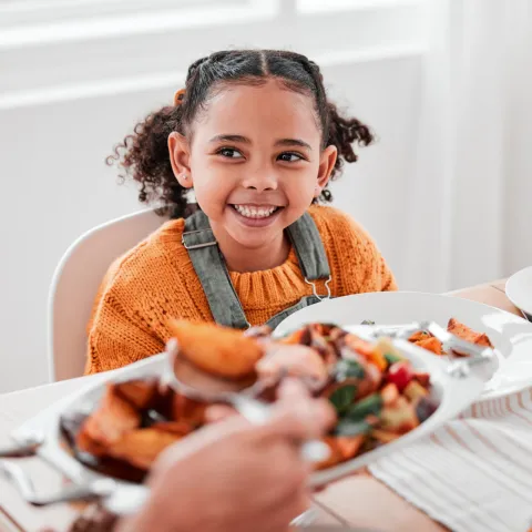 A girl smiling at the dinner table.