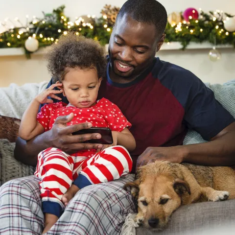 A father an son sit together on the couch during the holiday season. 