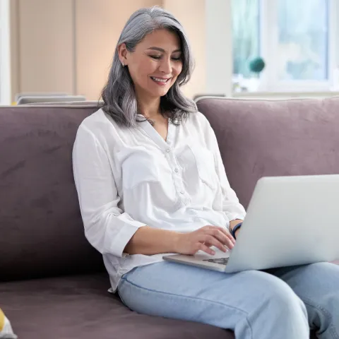A woman using her computer while sitting on the couch.