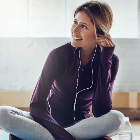 A woman wearing headphones and exercise clothes.
