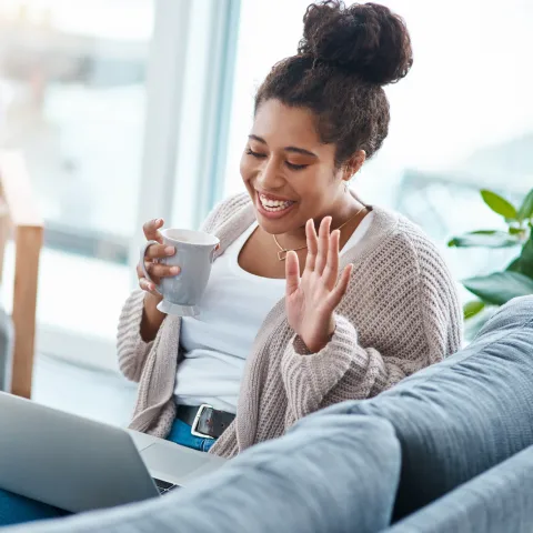 A woman waving to a friend on a video call. 