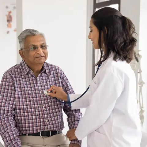 Female doctor checking the heart rate of a male patient.