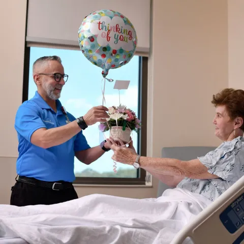 Team Member Volunteering at Hospital Delivering Balloons to Patient