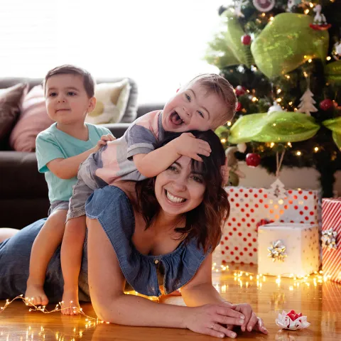 Caucasian mother with two sons laying under a Christmas tree.