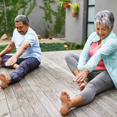 A couple doing leg stretches outdoors.