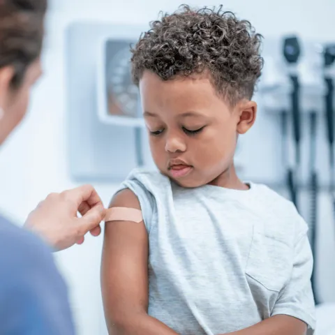 A young boy getting a band-aid after a flu shot.