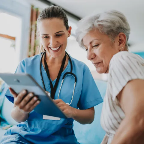 Nurse showing female patient tablet.