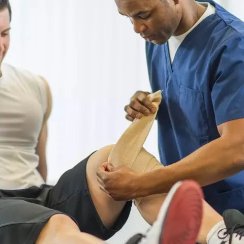 Physical Therapist Bandaging Patient's Knee