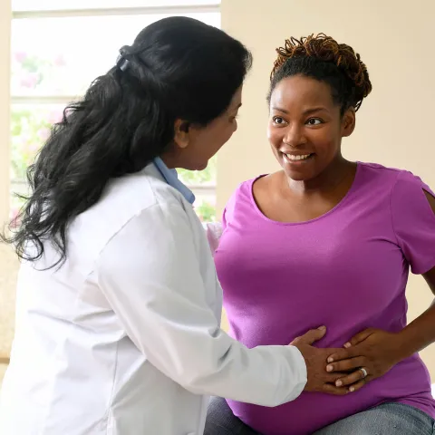 A nurse having a friendly conversation with a patient who is expecting a baby. 