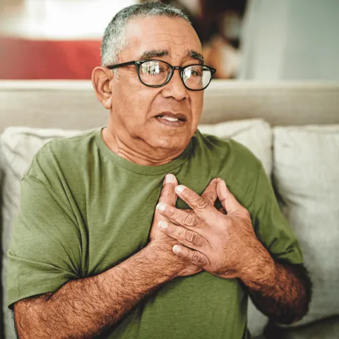 An older man holding his chest.