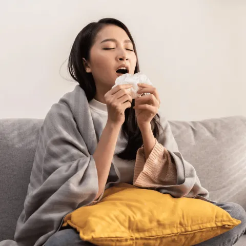 A woman sneezing into a tissue.