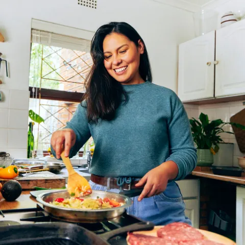 Woman cooking in kitchen smiling.