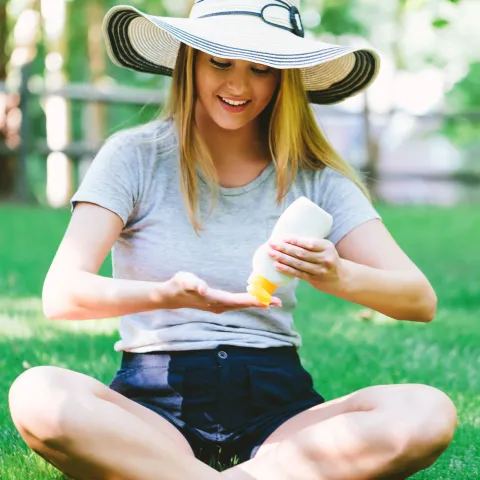 Woman Applying Sunscreen in Park