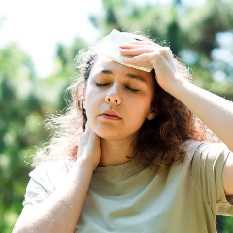 A woman wiping sweat from her brow while walking outdoors.