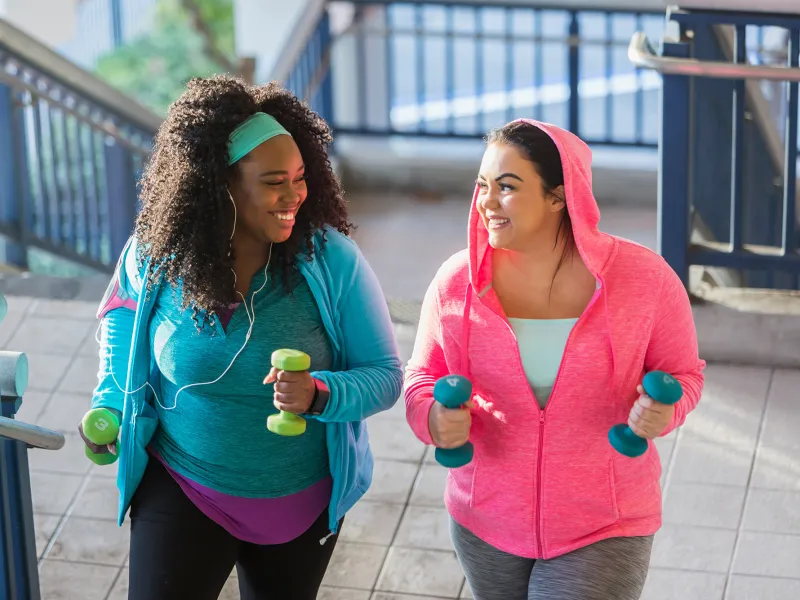 Two Women Running Outside With Weights