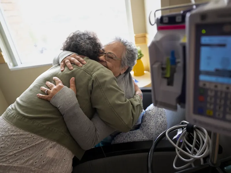 Woman comforting senior patient in hospital.