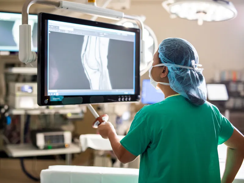 doctor in scrubs examining an x-ray in a surgical room