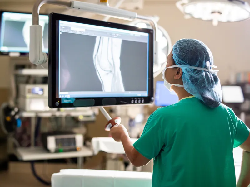 doctor in scrubs examining an x-ray in a surgical room