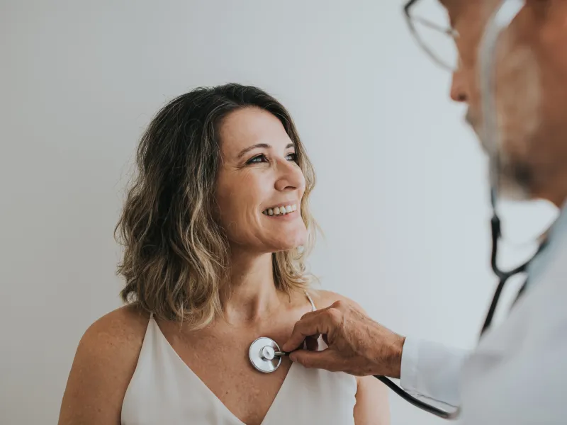 Doctor Listening to Female Patient Heartbeat