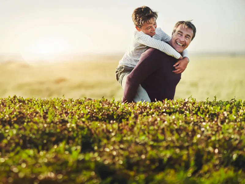 Father carrying son on back.