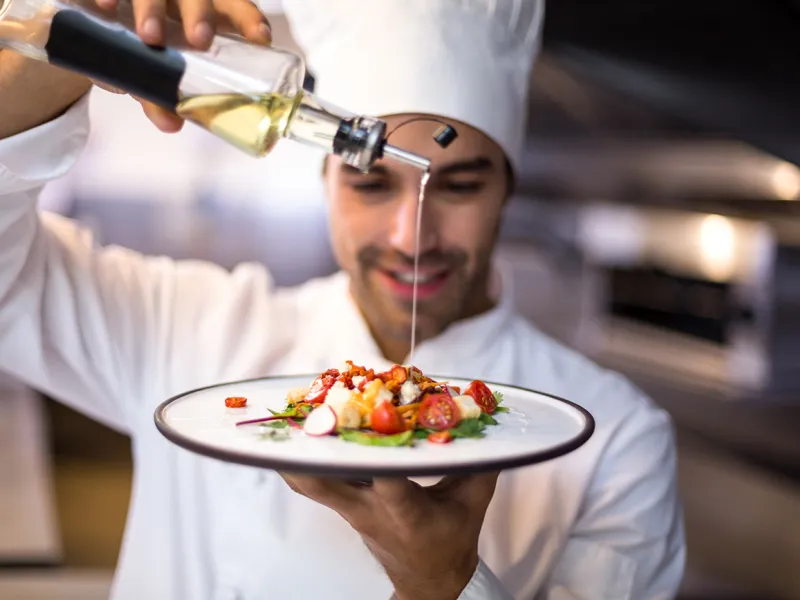Male Chef drizzling olive oil on plate