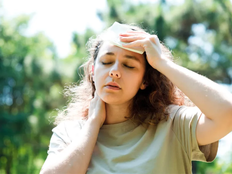 A woman wiping sweat from her brow while walking outdoors.