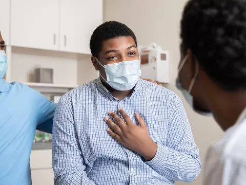 A Man Speaks to His Doctor in a Patient Room While Being Comforted with a Family Member.