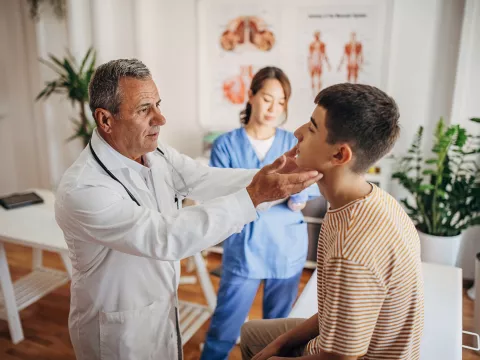 A Doctor Examines a Teenage Patients Face While a Nurse Takes Notes