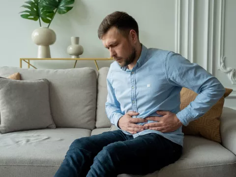 A Man Winces in Pain as He Hold's his Side