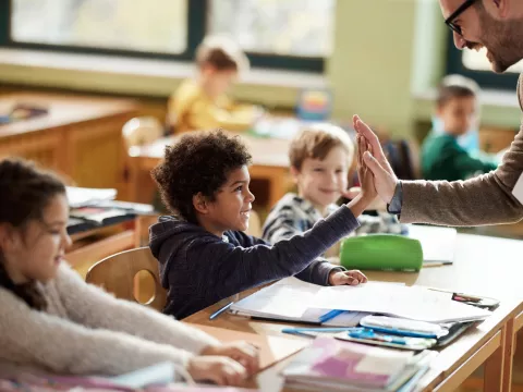 A Student High Fives His Teacher in the Classroom