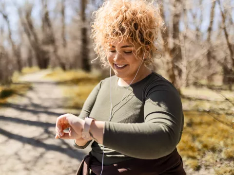 A Woman Checks Her Smart Watch While Going For a Run in the Park