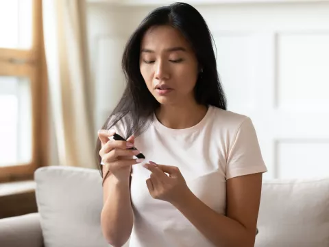A Woman Tests Her Glucose Levels with a Finger Medical Device