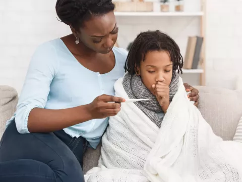 Mother Covering Sick Son With Blanket
