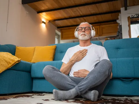 An older man meditating at home.
