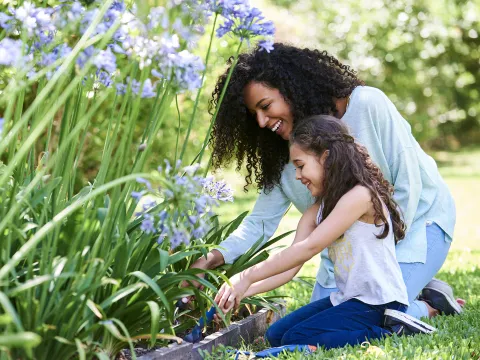 A girl and her mother planting flowers.