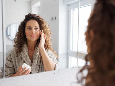 Female putting skin care on her face.