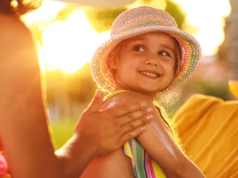 Mother supplying sunscreen to child outdoors.