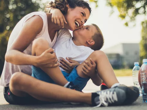 A mother and son take a water break on the basketball court during the summer.