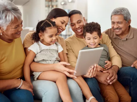 Hispanic Latino family on couch looking at iPad together.