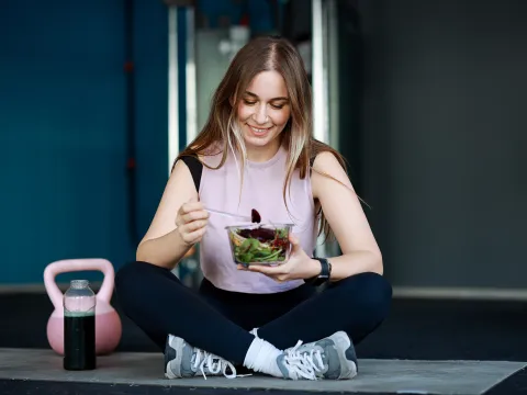Woman eating salad after excercising.