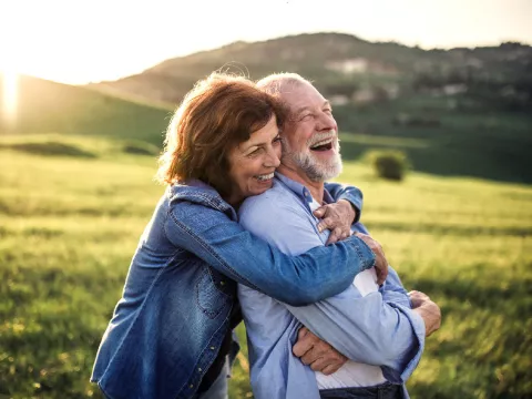 A Couple Hugs Out in a Field While Laughing
