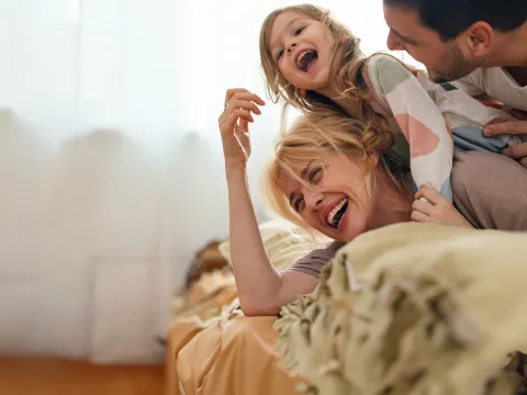 Family Laughing Together While Laying on a Bed