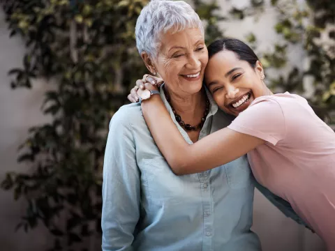 A Woman Hugs her Grandmother Outside in the Garden