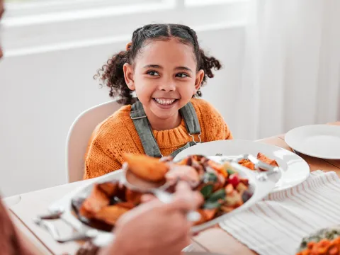 A girl smiling at the dinner table.